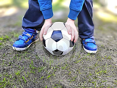 Boys legs and ball holding hands on green grass. Stock Photo